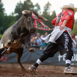 A man in a red shirt with a red bandana in his pocket runs from a charging bull